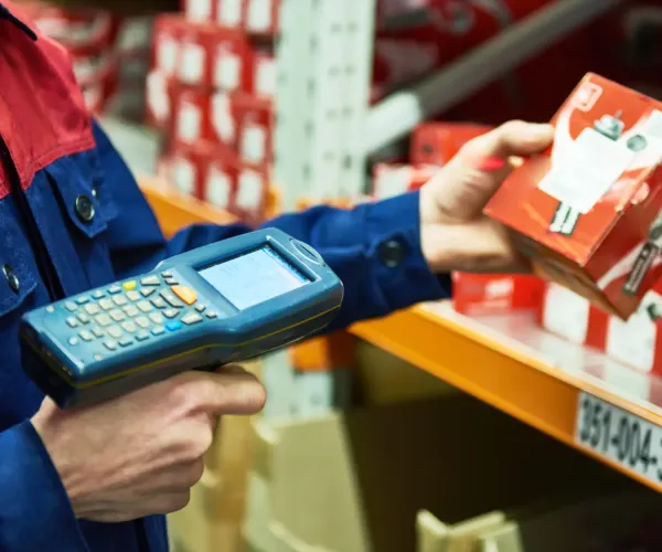 Handheld barcode scanner tracking packaged inventory in a warehouse for product traceability.
